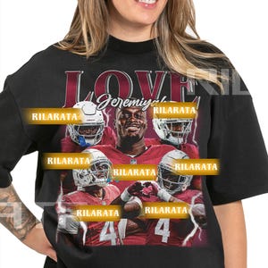 Może przedstawiać: Czarny, unisexowy t-shirt dla dorosłych z grafiką przedstawiającą gracza w futbol amerykański, słowem "LOVE" i imieniem "Jeremiyah". Koszulka zawiera również tekst "RILARATA" oraz liczby "41" i "4".