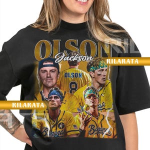 Peut inclure: T-shirt unisexe noir pour adulte avec un collage de joueurs de baseball en uniformes jaunes. Le t-shirt porte les noms "Olson" et "Jackson", ainsi que les mots "Banana" et "Rilarata".