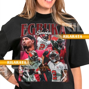 Könnte beinhalten: Schwarzes Unisex-T-Shirt für Erwachsene mit einer Grafik von Footballspielern. Das Shirt hat den Namen "EGBUKA" in großen roten Buchstaben. Das Shirt hat auch den Text "RILARATA" und den Text "READY CUSTOM DESIGNS".