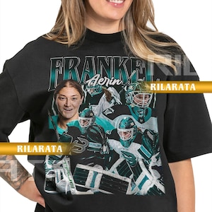 May include: Black adult unisex t-shirt featuring a teal and white graphic of a hockey player and the text "FRANKEN Aerin". The shirt also has the text "RILARATA" and "READY CUSTOM DESIGNS".
