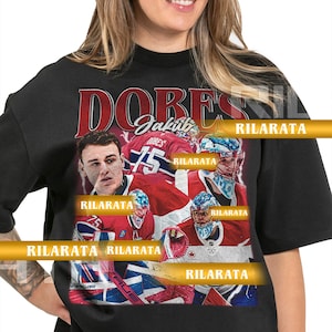 Könnte beinhalten: Schwarzes Unisex-T-Shirt für Erwachsene mit einem Hockey-Spieler-Design. Das Shirt hat das Wort "DOBES" in Rot und Weiß, zusammen mit dem Namen und der Nummer des Spielers. Das Shirt hat auch den Text "RILARATA" und "READY CUSTOM DESIGNS".