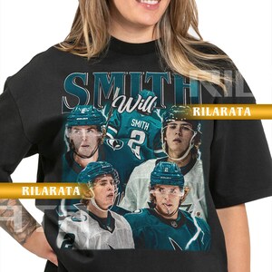 Könnte beinhalten: Schwarzes Unisex-T-Shirt für Erwachsene mit einem Hockey-Motiv. Das Shirt zeigt eine Collage von Hockeyspielern, den Namen "Smith" und die Nummer 2. Der Text "Will Smith" und "Rilarata" sind ebenfalls aufgedruckt. Das Design verwendet Teal und Weiß.