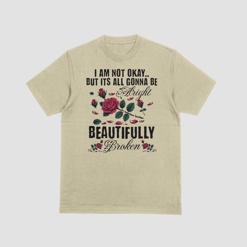 May include: Beige t-shirt with the text "I AM NOT OKAY.. BUT ITS ALL GONNA BE Alright BEAUTIFULLY Broken" in black and a red rose graphic. The graphic includes red roses and green leaves.