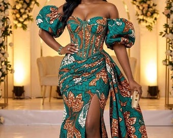May include: A floor-length off-the-shoulder dress featuring a corset-style bodice and voluminous puff sleeves. The garment is crafted from a teal fabric with a repeating orange and white leaf pattern, including a high side slit and a draped train.