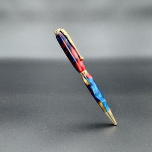 Handgemaakte acrylpen – gouden rand | Rode, blauwe en amberkleurige werveling | Unieke, door draaibank gedraaide, slanke cadeaupen