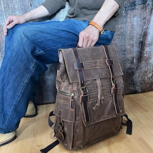 May include: A brown leather backpack with multiple pockets and buckles. The backpack has a flap with a buckle closure and a drawstring closure. The backpack is made of a durable material and has a vintage look.