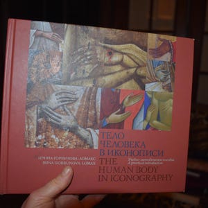 Può includere: Un libro rosso intitolato "Il corpo umano nell'iconografia" con un'immagine multicolore di una figura umana sulla copertina. Il libro è scritto da Irina Gorbunov e Irina Torishcheva.