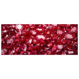 Op de afbeelding: Een close-up van een stapel gefacetteerde, dieprode edelstenen. De edelstenen zijn dicht opeengepakt, met licht dat weerkaatst op hun vele oppervlakken. Het algehele effect is een rijke, sprankelende weergave van kleur en glans.