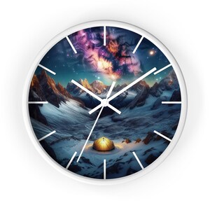 May include: White wall clock featuring a mountain landscape with a starry sky. The clock face shows a tent illuminated in a snowy valley. The clock hands are white, and the frame is white.