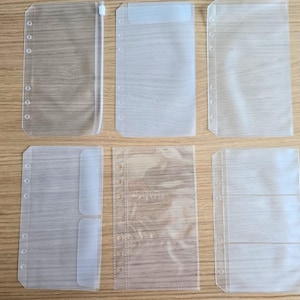 May include: Six clear plastic pockets with holes for a binder. The pockets are different sizes and have different numbers of compartments.