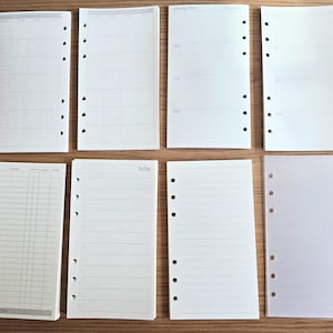May include: A set of eight blank, white, lined, and gridded paper inserts for a six-ring binder. The inserts have holes on the left side and are designed for use with a planner or journal.