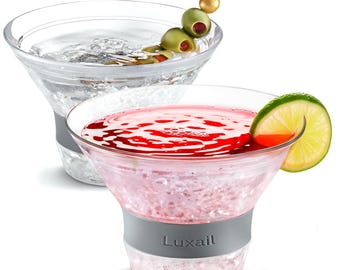 May include: Two clear martini glasses filled with chilled beverages. One glass contains a clear liquid with olives on a skewer, the other has a pink drink with a lime wedge. Both glasses have a gray band with the word "Luxail".