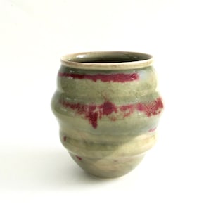 May include: A ceramic vase with a green glaze and red accents. The vase has a rounded shape with a slightly flared opening.