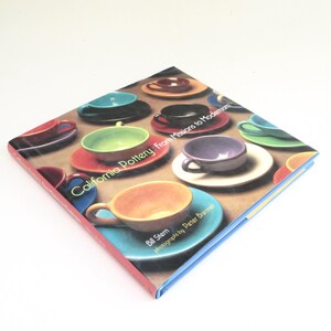 May include: A book titled "California Pottery: From Missions to Modernism" by Bill Stern with photographs by Peter Brenner. The cover features a colorful display of ceramic cups and saucers.