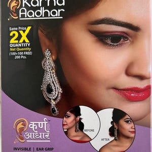 May include: A product box featuring a close-up of a woman's face with dramatic eye makeup and red lipstick. The box displays the text "Karna Aadhar" and "Invisible Ear Grip". The image also shows a before and after comparison of the product's effect.