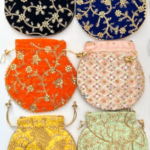 May include: A collection of six round, embroidered drawstring pouches in various colors. The pouches feature floral patterns and gold-colored embellishments. Colors include black, blue, orange, pink, yellow, and green.