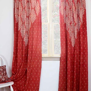 May include: A pair of red curtains with a white floral pattern. The curtains are hanging in a window and are pulled back to reveal the view outside.