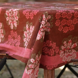 May include: A brown tablecloth with a pink and white floral pattern. The tablecloth is made of cotton and has a soft, textured feel.