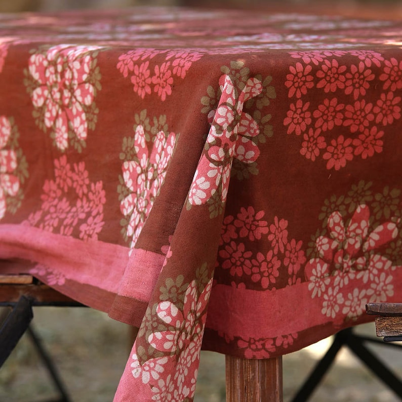 May include: A brown tablecloth with a pink and white floral pattern. The tablecloth is made of cotton and has a soft, textured feel.