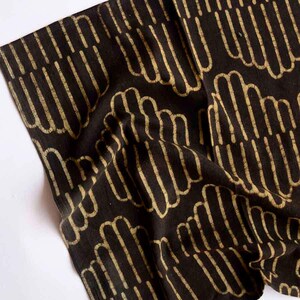 May include: Black fabric with a white pattern of repeating curved lines. The fabric is folded and textured.