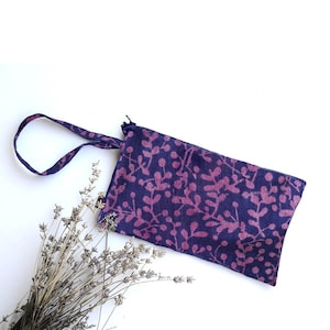 May include: A small purple and pink zippered pouch with a floral pattern and a fabric handle.
