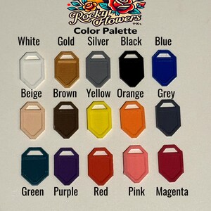 May include: A colour palette chart featuring fifteen shield-shaped tags in various colours including white, gold, silver, black, blue, beige, brown, yellow, orange, grey, green, purple, red, pink, and magenta, with the text Rocky Flowers 990s.
