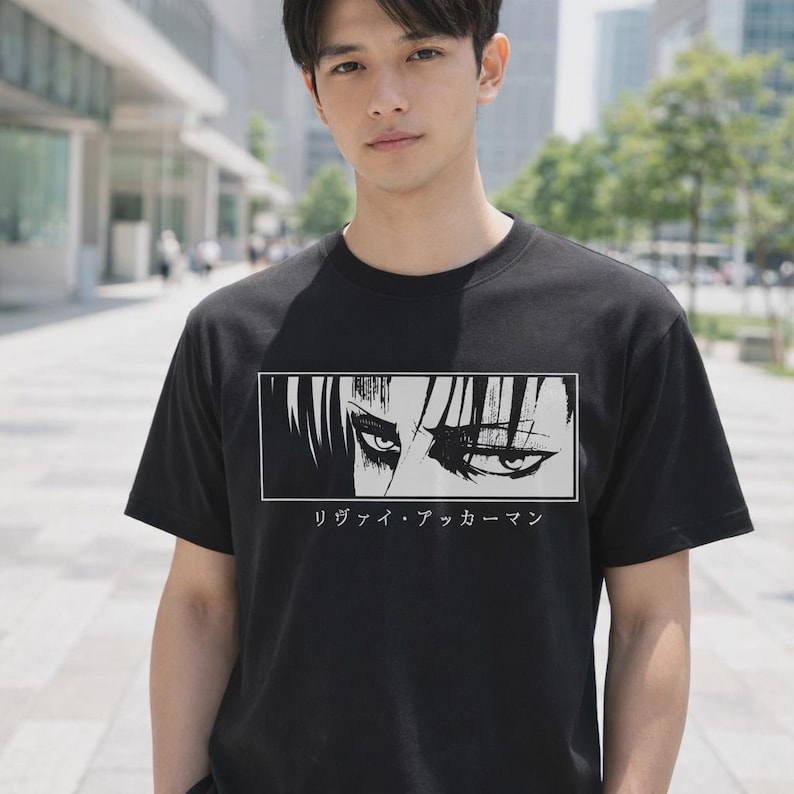 May include: Black crew neck t-shirt with a graphic of stylized eyes in a white rectangle, and Japanese text beneath. The t-shirt is a classic fit.