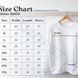 May include: A white Gildan 18000 sweatshirt hangs on a wooden hanger next to a size chart. The chart displays measurements in inches for width, length, and sleeve length, ranging from size S to 5XL.
