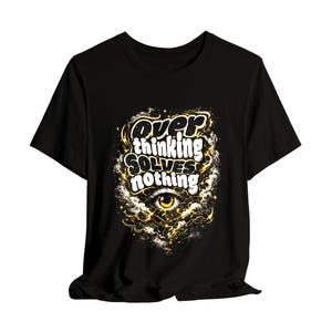 Puede incluir: Camiseta negra con la frase "Overthinking Solves Nothing" en letras blancas y amarillas. El diseño incluye un ojo y formas de nubes.