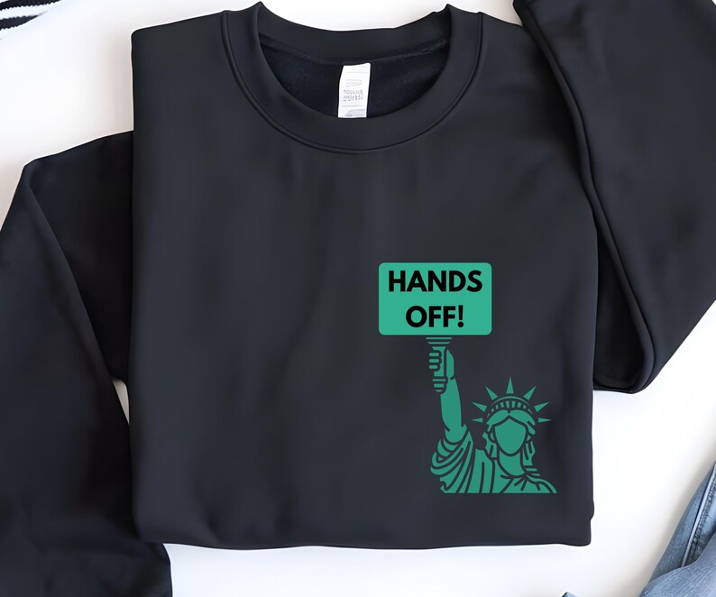 May include: Black sweatshirt with a green graphic of the Statue of Liberty holding a sign that says "Hands Off!"