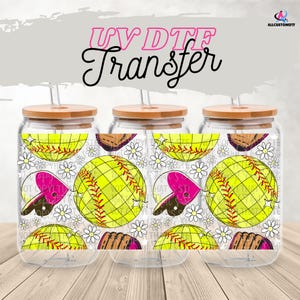 Könnte beinhalten: Drei Glasbecher mit Bambusdeckeln und Strohhalmen. Jeder Becher hat ein UV-DTF-Transferdesign mit einem gelben Softball, einem rosa Softballherz, einem braunen Handschuh und weißen Gänseblümchen. Der Text "UV DTF Transfer" steht oben.