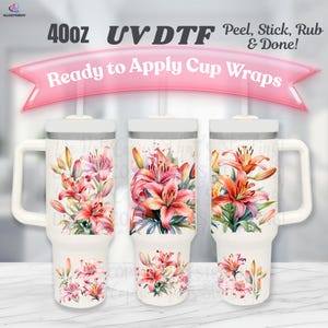 May include: Three white 40oz tumblers with handles, each decorated with a colourful floral design of pink and orange lilies. The text "Ready to Apply Cup Wraps" is displayed on a pink banner above the tumblers. The tumblers are labelled "40oz UV DTF".