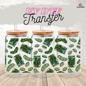 May include: Three clear glass beverage cups with bamboo lids and straws. The cups feature a repeating pattern of green pickles and jars of pickles. The text "UV DTF Transfer" is above the cups.