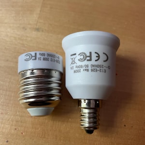 May include: Two white and silver light bulb adapters. One adapter is E26-E12, and the other is E12-E26. The adapters have the following text: E12-E26 Max 200W 0~250VAC 50/60Hz 2A and E26-E12 200W 2A 0-250VAC 60Hz.