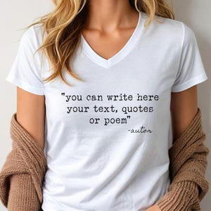 May include: A white V-neck t-shirt featuring black typewriter-style text that reads, "you can write here your text, quotes or poem" followed by "-autor" in a cursive script font. The shirt is worn with a brown knit cardigan draped over the shoulders.