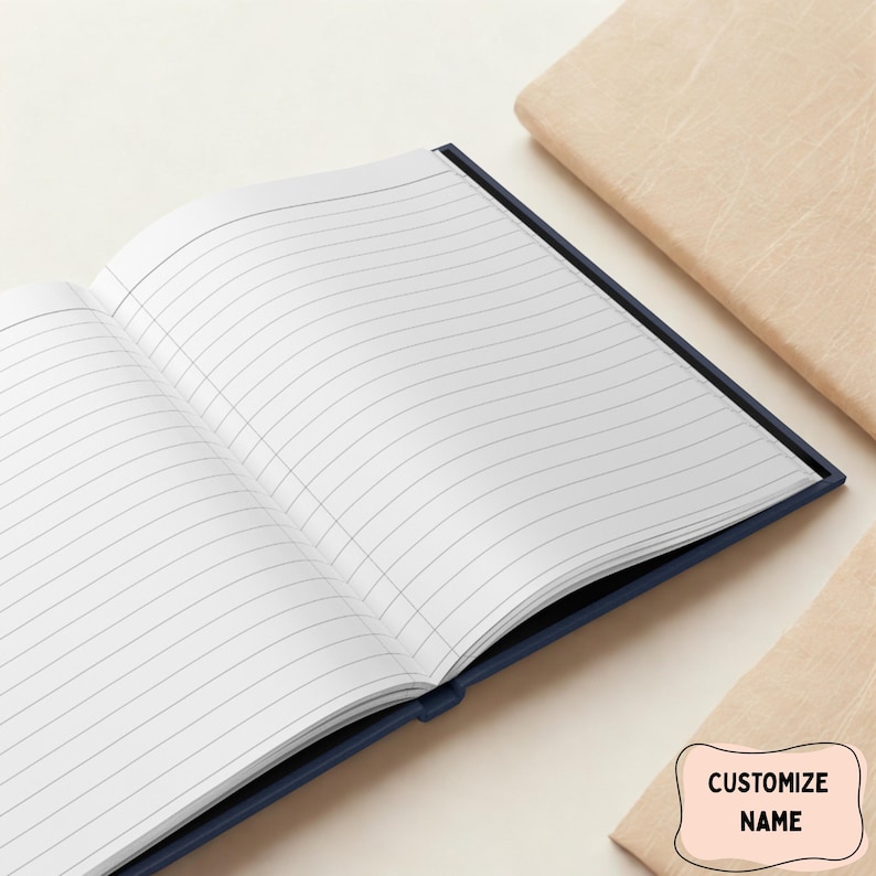 May include: An open, lined notebook with a dark blue cover. The pages are white with gray lines. The notebook is next to two tan-colored, closed notebooks. A small, light pink label with the text "CUSTOMIZE NAME" is in the bottom right corner.