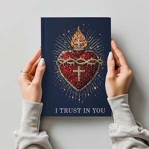 May include: A navy blue journal featuring a detailed illustration of a red heart adorned with a crown of thorns, a cross, and a golden flame. The text "I TRUST IN YOU" is printed at the bottom of the journal.