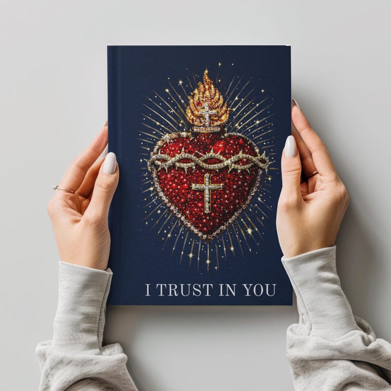 May include: A navy blue journal featuring a detailed illustration of a red heart adorned with a crown of thorns, a cross, and a golden flame. The text "I TRUST IN YOU" is printed at the bottom of the journal.