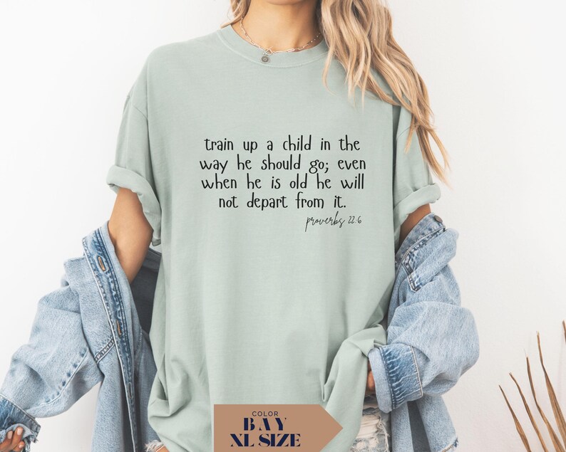 May include: A light green t-shirt with the text "train up a child in the way he should go; even when he is old he will not depart from it. Proverbs 22:6" in black. The shirt is a relaxed fit.