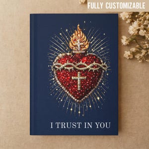 May include: A navy blue journal with a detailed illustration of a Sacred Heart. The heart is red with a crown of thorns and a cross, surrounded by gold accents and a golden flame. The text "I TRUST IN YOU" is at the bottom.
