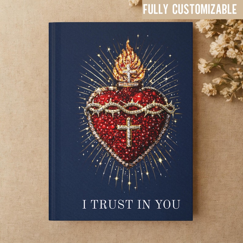 May include: A navy blue journal with a detailed illustration of a Sacred Heart. The heart is red with a crown of thorns and a cross, surrounded by gold accents and a golden flame. The text "I TRUST IN YOU" is at the bottom.