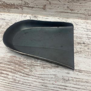May include: A black metal scoop with a curved handle. The scoop is made of metal and has a smooth, shiny finish.