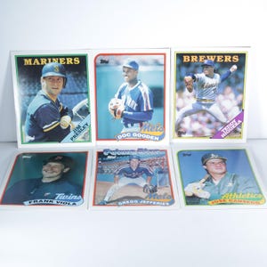 May include: Six vintage baseball trading cards featuring players from the Mariners, Mets, Brewers, Twins, and Athletics. The cards have colorful borders and player images, with names and team logos visible. The cards are from the Topps brand.