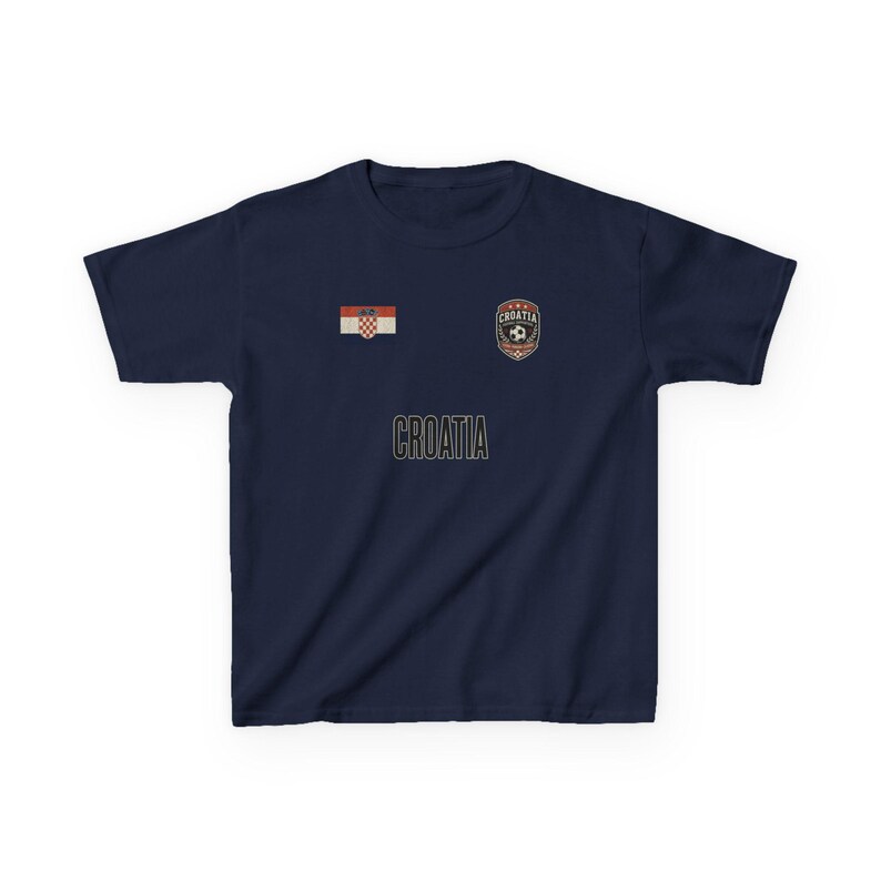May include: Navy blue t-shirt featuring the word "CROATIA" in a gold font. The shirt has a Croatian flag patch and a soccer crest. The shirt is a solid color and has short sleeves.