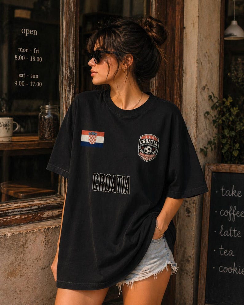 May include: Black t-shirt with the word "CROATIA" printed across the front. The shirt features the Croatian flag and a soccer emblem. The image also shows a cafe's open hours.