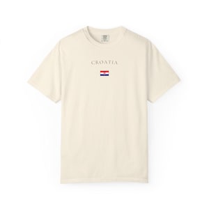 Peut inclure: T-shirt ivoire avec le mot "CROATIA" imprim&eacute; au-dessus d'un petit drapeau croate. Le t-shirt est de couleur unie, &agrave; manches courtes et col rond. Le mot "IVORY" est imprim&eacute; en grandes lettres en bas.