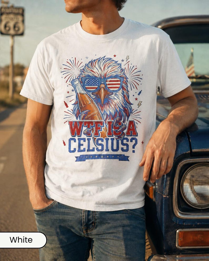 May include: A white t-shirt featuring a graphic of a bald eagle wearing American flag sunglasses and holding a glass bottle. The text reads "WTF IS A CELSIUS?" in red and blue lettering, surrounded by firework illustrations and small stars.