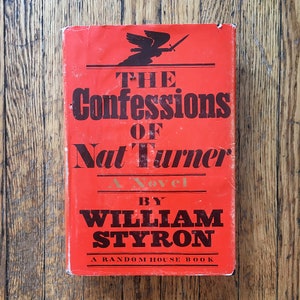 May include: A red hardcover book with the title "The Confessions of Nat Turner" and the author "William Styron". The book is a novel and is a Random House book.