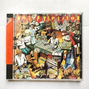 May include: A CD case with a colorful illustration of a band in a recording studio. The title of the album is "Escape to the Asylum of Dub" by Mad Professor. The album cover features a mix of bright colors, including yellow, red, blue, and green.
