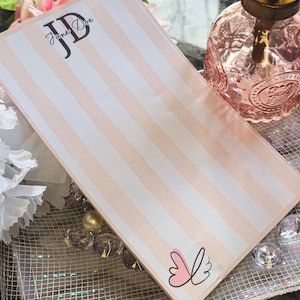 Op de afbeelding: Rechthoekig notitieblok met verticale roze en witte strepen. De initialen "JD" en de naam "Jane Doe" staan linksboven. Een vlindergrafiek staat rechtsonder. Geschikt voor briefpapier.